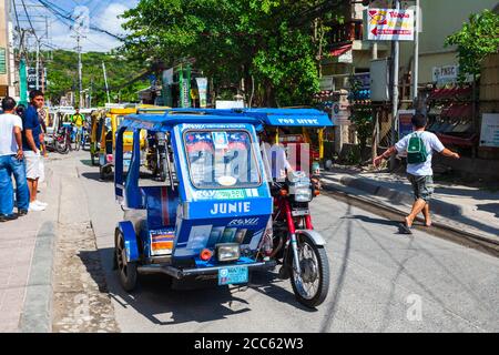 BORACAY, PHILIPPINES - MARCH 04, 2013: Tricycle at the main street in Boracay island. Tricycle is a very popular public taxi transport in Philippines. Stock Photo