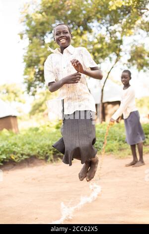 South Sudanese refugee children jump rope together in the Palabek Refugee Camp in northern Uganda, East Africa. Stock Photo
