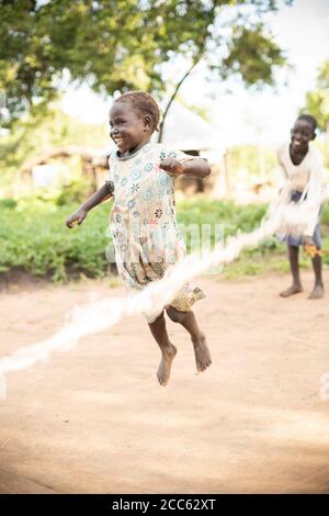 South Sudanese refugee children jump rope together in the Palabek Refugee Camp in northern Uganda, East Africa. Stock Photo
