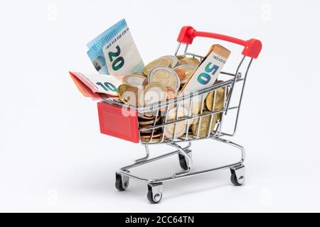 Shopping cart full of euro coins and banknotes, white background. Concepts of currency value, inflation and purchasing power Stock Photo