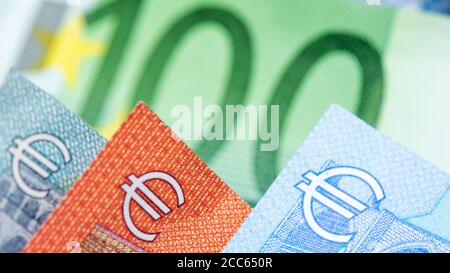 Close-up view of euro symbols on 5, 10, 20 euro banknotes. 100 euro green bank note in the background Stock Photo