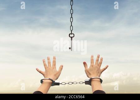 person with handcuffed hands tries to take the keys to free themselves but they are too far away Stock Photo
