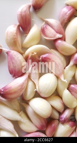Top view close up of red-white garlic cloves on white ceramic background. Stock Photo