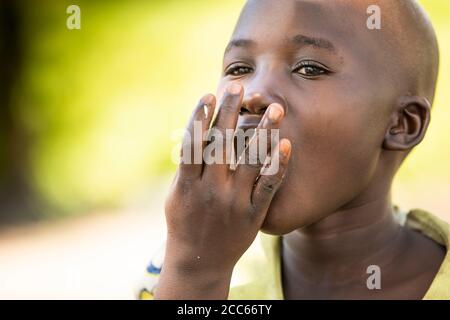 An 8-year-old girl child from South Sudan eats with her hands in Palabek Refugee Settlement in Northern Uganda, East Africa. Stock Photo