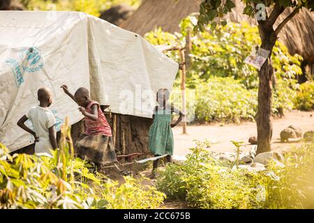 Refugees from South Sudan live in makeshift mud and grass thatch homes covered in tarpaulin sheets in Palabek Refugee Settlement in northern Uganda, East Africa. Stock Photo