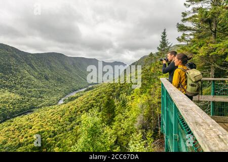 Travel couple hikers hiking in Canada, Quebec Jacques Cartier National Park. Tourists hiking taking photo with camera at view of mountain landscape in Stock Photo
