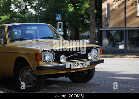 Classic old yellow colored Volvo with round headlights under some shade with a green traffic light on the background. Taken in Tampere Finland. Stock Photo