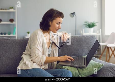 Young smiling woman communicating with somebody on laptop during online meeting Stock Photo