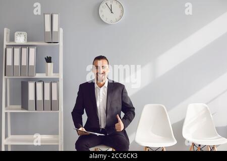 A young brunette holds a resume in her hands waiting for an interior view of a new job in office. Stock Photo