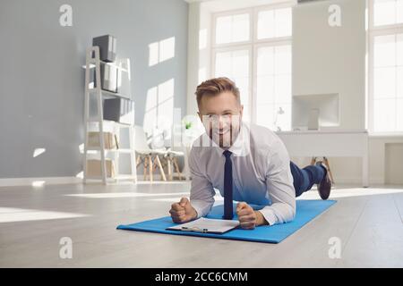 Businessman doing abs strap exercises while lying in the office. Stock Photo