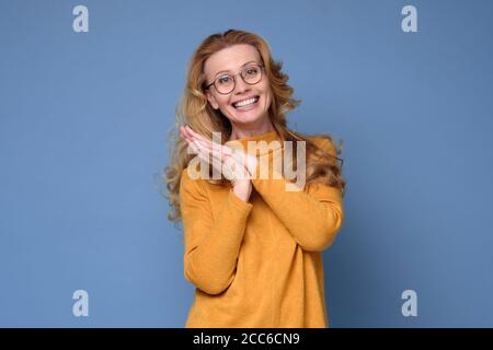 Woman looking at camera and smiling while standing against blue background. Stock Photo