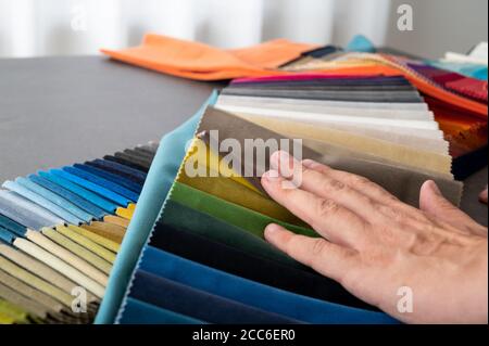 Hand resting on some multi colored velvet samples part of the selection process Stock Photo