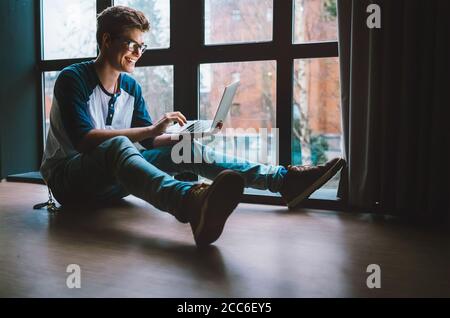 Guy with laptop sits on the floor at home Stock Photo