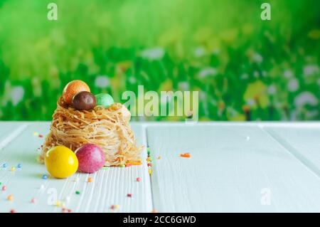 Colored chocolate eggs in sweet nest on white background Stock Photo