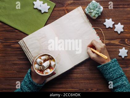 Female hands writing in notebook on wooden background Stock Photo