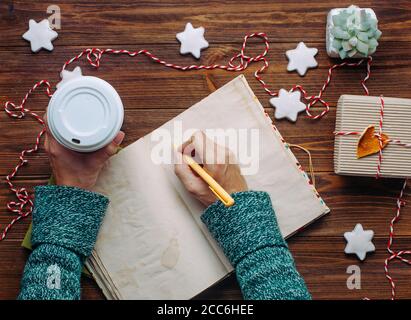 Female hands writing in notebook on wooden background Stock Photo
