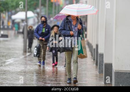 Sheffield, UK. 19th Aug 2020. A woman shelters from the rain beneath an umbrella during a heavy downpour in Sheffield this afternoon. Large parts across the UK will hit by the rain today. Credit: Ioannis Alexopoulos/Alamy Live News Stock Photo