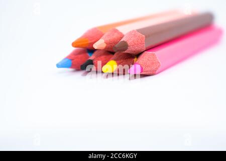 Seven different colored wood pencil crayon placed on a white paper background Stock Photo