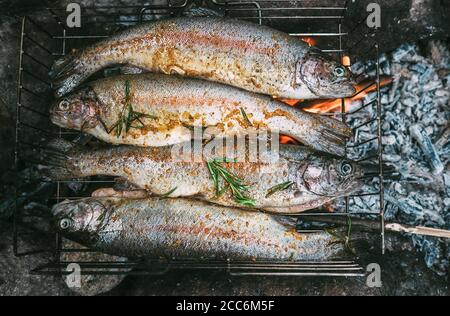 Fresh trouts with spices and herbs are in grilling grid over the campfire Stock Photo