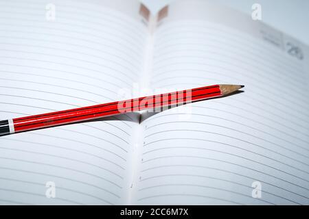 close up shot of blank paper daily notebook page with pencils Stock Photo