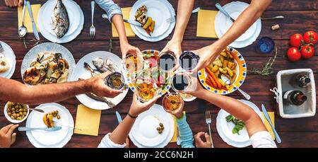 Big family dinner. Vertical top view on served table and hands with clinking goblets Stock Photo