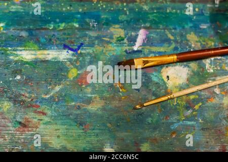 Brushes on an easel stained with paints in the artist's studio. Stock Photo