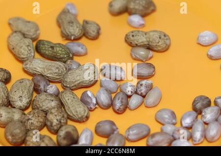 Peanuts in shells on yellow background. Raw peanuts top view isolated on yellow plate backgrounds Stock Photo