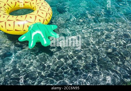 Crystal clear water in the sea lagoon with bright inflatable pineapple pool ring Stock Photo