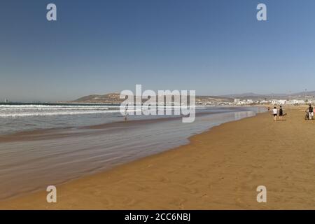 Agadir, Morocco.Feb.9,2019:Beach with tourist walking and Moroccan motto on the mountain. Writing on the hillside meaning, God, Country, King. People Stock Photo