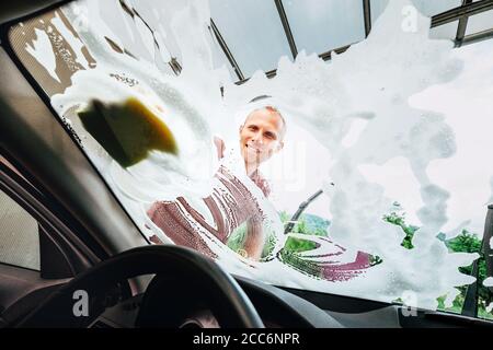 Man washes car front windows with soap foam Stock Photo