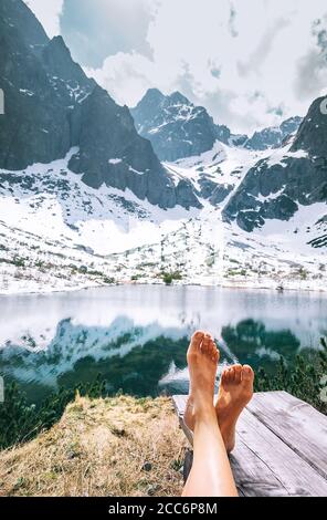 Woman traveler feet without shoes.  Relax time after walk. Beautiful mountain lake stop point Stock Photo