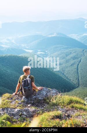 Young man tourist rest on the top of hill with beautiful valley panorama Stock Photo