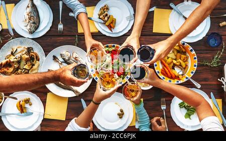 Big family dinner. Top view on served table and hands with clinking goblets Stock Photo