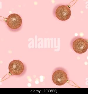 Circle frame made of golden Christmas baubles on a pink pastel background. Greeting card template with copy space. Stock Photo