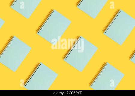 Pattern made of mint spiral copybooks on a yellow background. Back to school concept. Stock Photo