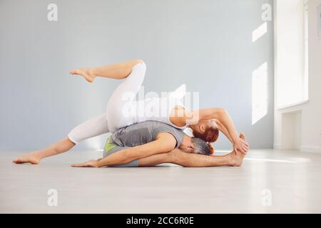 Yoga couple practice acro yoga on the floor in a studio class. Stock Photo