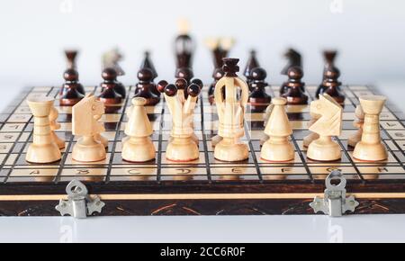 Black and white chess pieces arranged on chess board before start of gameplay as two armies in front of each other Stock Photo