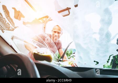 Man washes his car front window Stock Photo