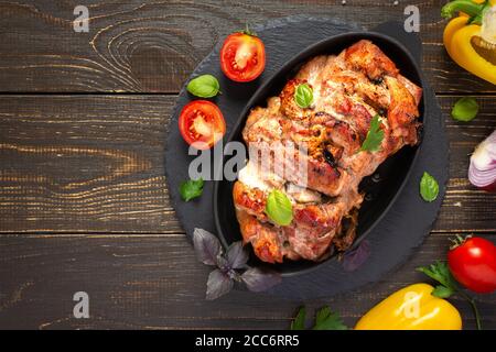 Baked pork ham on a wooden background, fried piece of meat with spices, fresh vegetables, top view Stock Photo