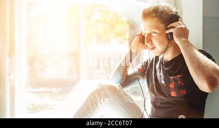 Teenager listening the music sitting on windowsill Stock Photo