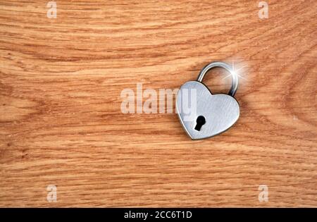 silver heart shaped padlock on wooden background top view Stock Photo