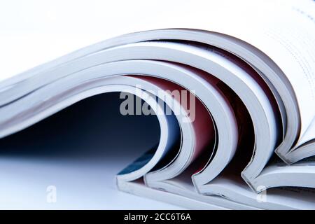 stack of open glossy magazines on white background closeup Stock Photo