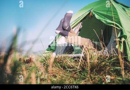 Traveler legs in socks stick out from camping tent Stock Photo