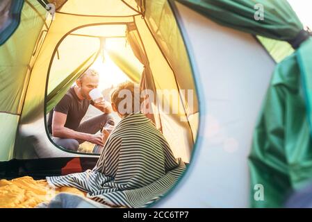 Family lisure concept image. Father and son prepare for camping in mountain, drink tea in ten Stock Photo