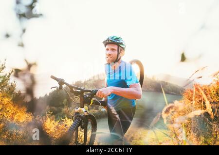 Cyclo-cross competition member Man mountain biker carrying his bike up on hill top Stock Photo