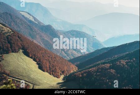 Tiny retro plane fly over the mountain hills Stock Photo