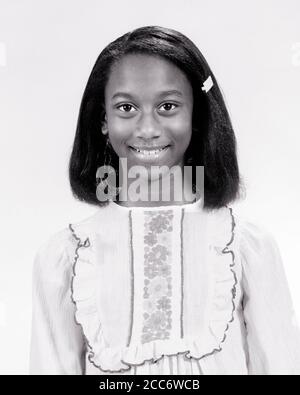 1970s PORTRAIT AFRICAN-AMERICAN TEENAGE GIRL WEARING TRENDY EMBROIDERED RUFFLED PEASANT BLOUSE SMILING LOOKING AT CAMERA  - g8405 HAR001 HARS HALF-LENGTH PERSONS TEENAGE GIRL TRENDY CONFIDENCE EXPRESSIONS B&W EYE CONTACT HAPPINESS CHEERFUL AFRICAN-AMERICANS AFRICAN-AMERICAN BLACK ETHNICITY PRIDE BLOUSE SMILES JOYFUL STYLISH TEENAGED GROWTH JUVENILES PEASANT RUFFLED BLACK AND WHITE EMBROIDERED HAR001 OLD FASHIONED AFRICAN AMERICANS Stock Photo