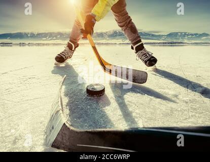 Father and son playing hockey on the frozen high mountain lake ice. Stock Photo