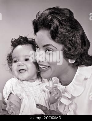 1960s SMILING AFRICAN-AMERICAN WOMAN MOTHER POSING CHEEK TO CHEEK WITH HER LAUGHING BABY GIRL DAUGHTER - n1060 HAR001 HARS MOTHERS EXPRESSION OLD TIME FUTURE NOSTALGIA MEDIA INDUSTRY OLD FASHION 1 JUVENILE FACIAL LAUGH SECURITY YOUNG ADULT TEAMWORK INFANT STRONG PLEASED FAMILIES JOY LIFESTYLE FEMALES STUDIO SHOT HEALTHINESS HOME LIFE LADIES DAUGHTERS PERSONS INSPIRATION CARING CUTOUT CONFIDENCE EXPRESSIONS B&W HAPPINESS HEAD AND SHOULDERS CHEERFUL PROTECTION STRENGTH AFRICAN-AMERICANS AFRICAN-AMERICAN EXCITEMENT BLACK ETHNICITY PRIDE POSING SMILES CONNECTION CONCEPTUAL JOYFUL STYLISH Stock Photo
