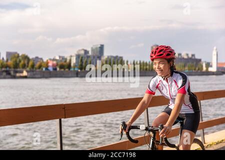 Urban biking girl riding road bike cycling in the city. Happy cyclist with downtown background by the St Lawrence river, Montreal, Canada Stock Photo